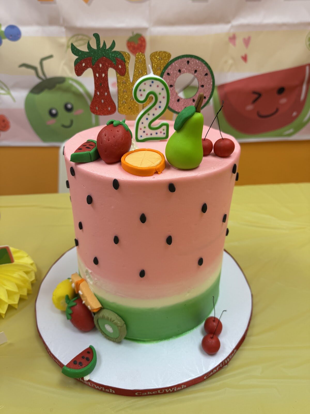 Watermelon-themed second-birthday cake with fruit accents