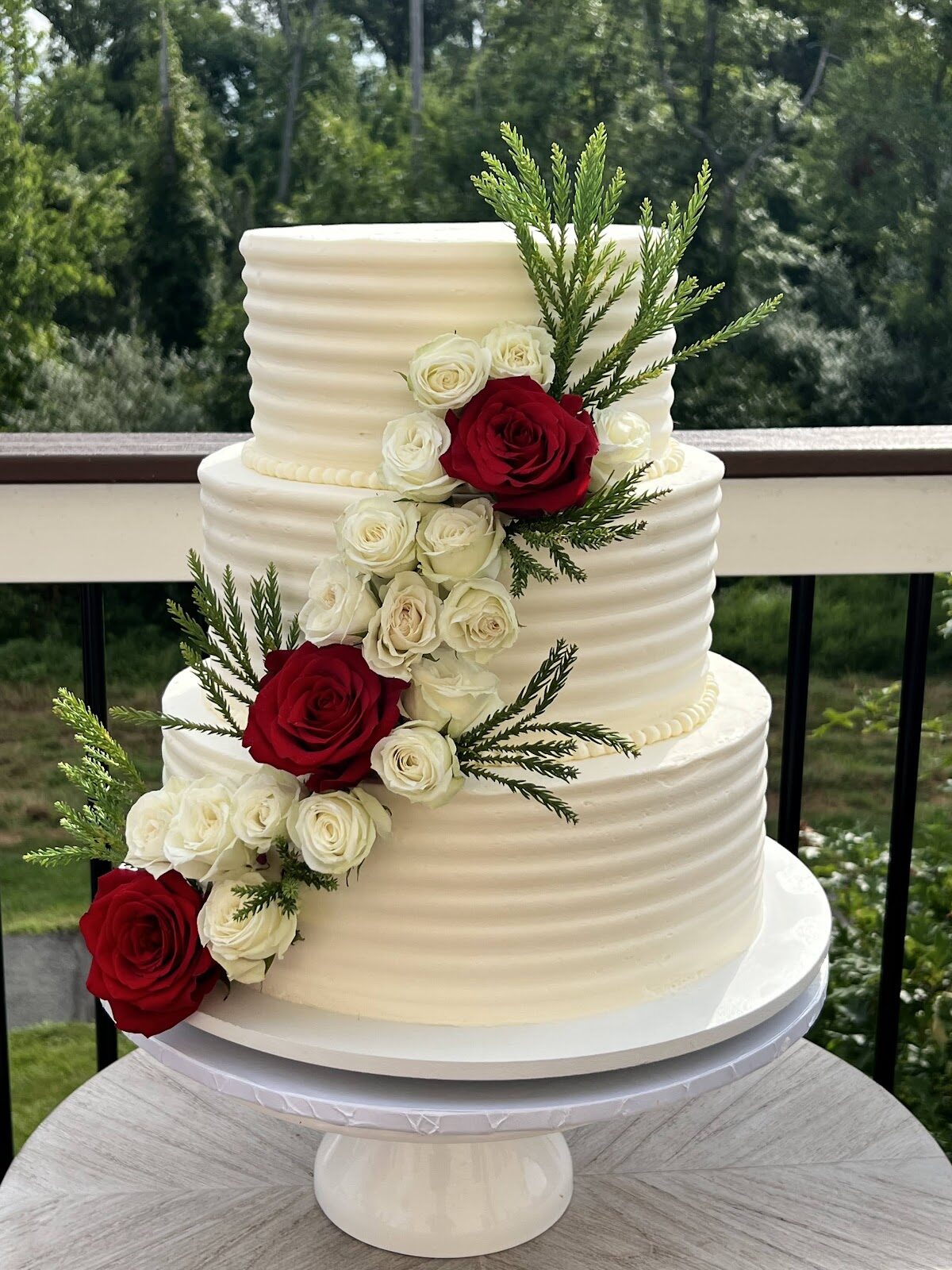 Textured white two-tier wedding cake with cascading red and white roses