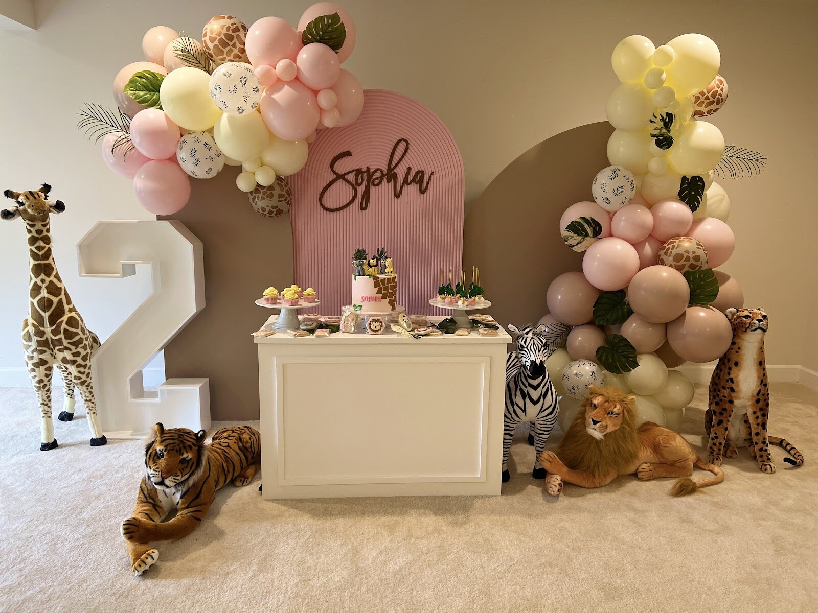 Safari number-two cake set against a balloon garland backdrop
